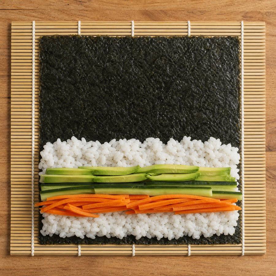 Sushi Nori Blätter mit Reis, Avocado, Gurke und Karotte auf Bambusmatte